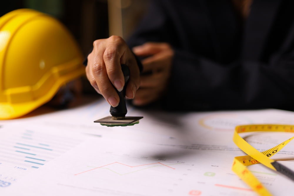 Close-up of a construction supervisor in New orleans stamping approval on project documents, highlighting attention to detail and project management.