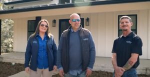 Members of a construction company in New Orleans, Nola Build, standing proudly in front of a newly completed home.